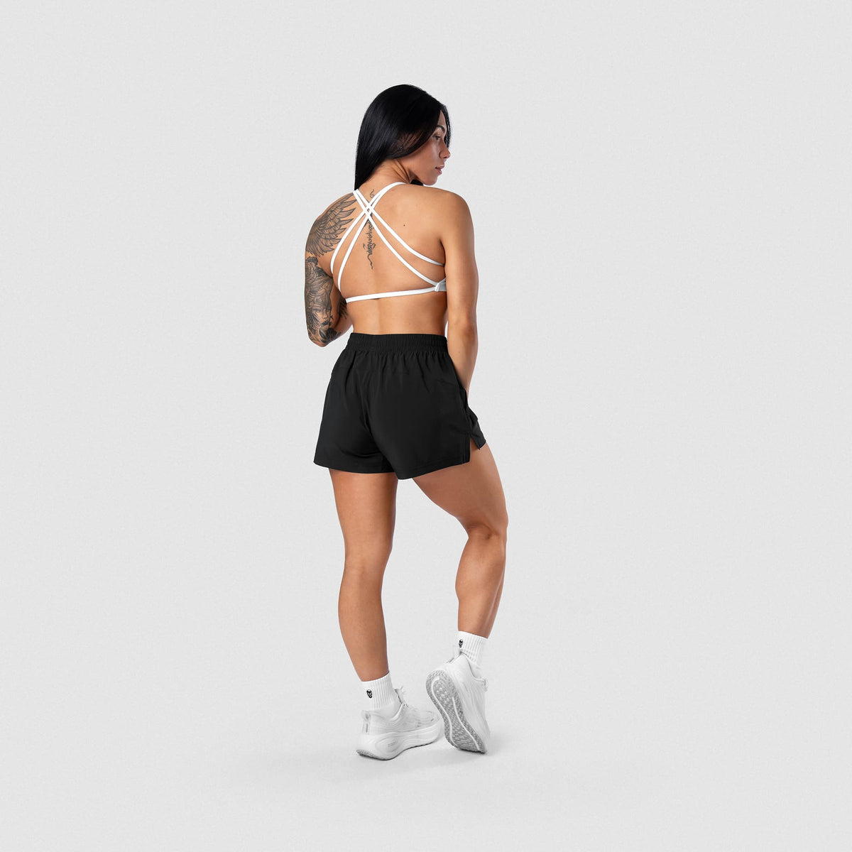 Female model wearing the Axis Open Back Bra - White full-body back view