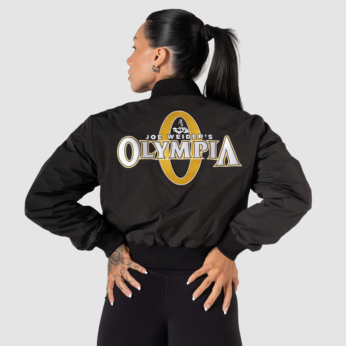 Champions Gold Crop Bomber Jacket | Back model feature showcasing the large "Joe Weirder's Olympia" logo