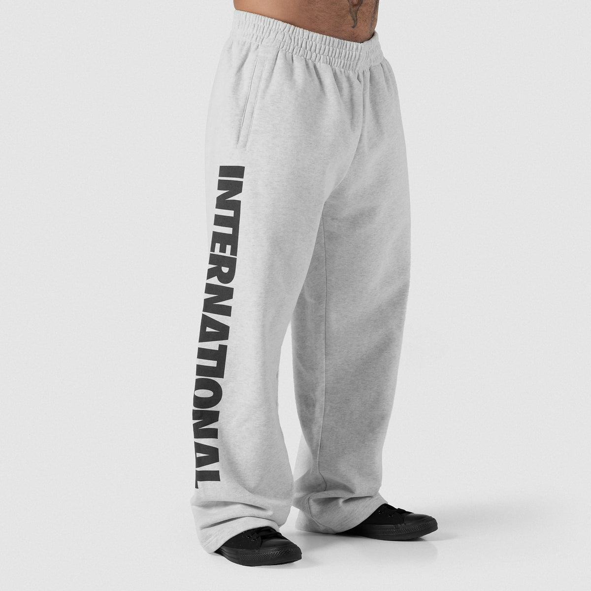 Male model wearing the Olympia International Division Straight-Leg Jogger in gray, showing the "INTERNATIONAL" logo down the side f the right pant leg