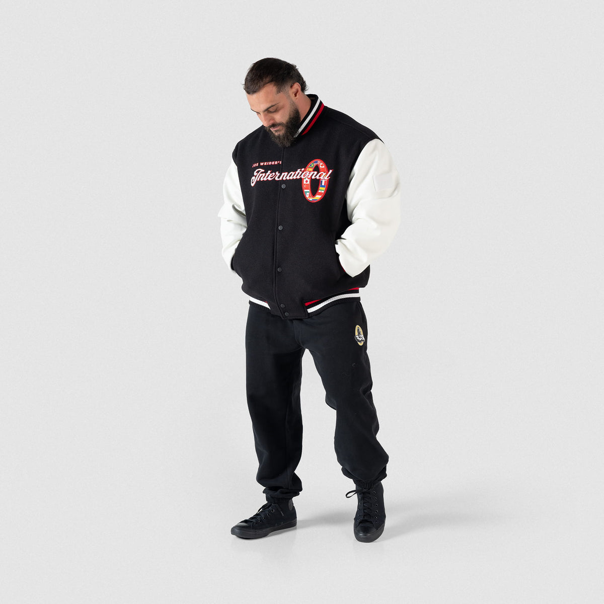 Olympia International Division Varsity Jacket in Black – Full Body On Model, Front View