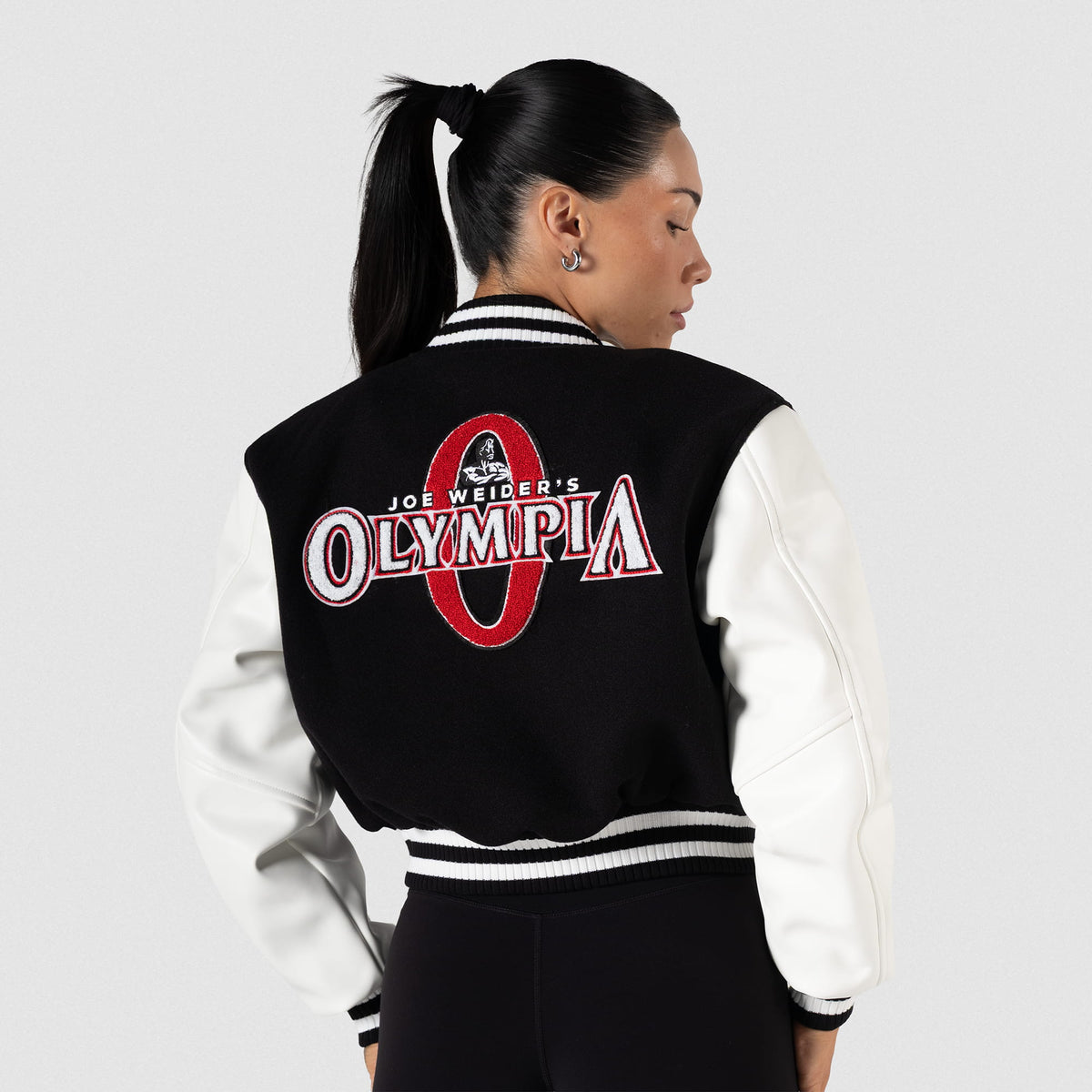 Signature Crop Varsity Jacket | Back view of model, showcasing large Joe Weider's Olympia and "O" logo on the back