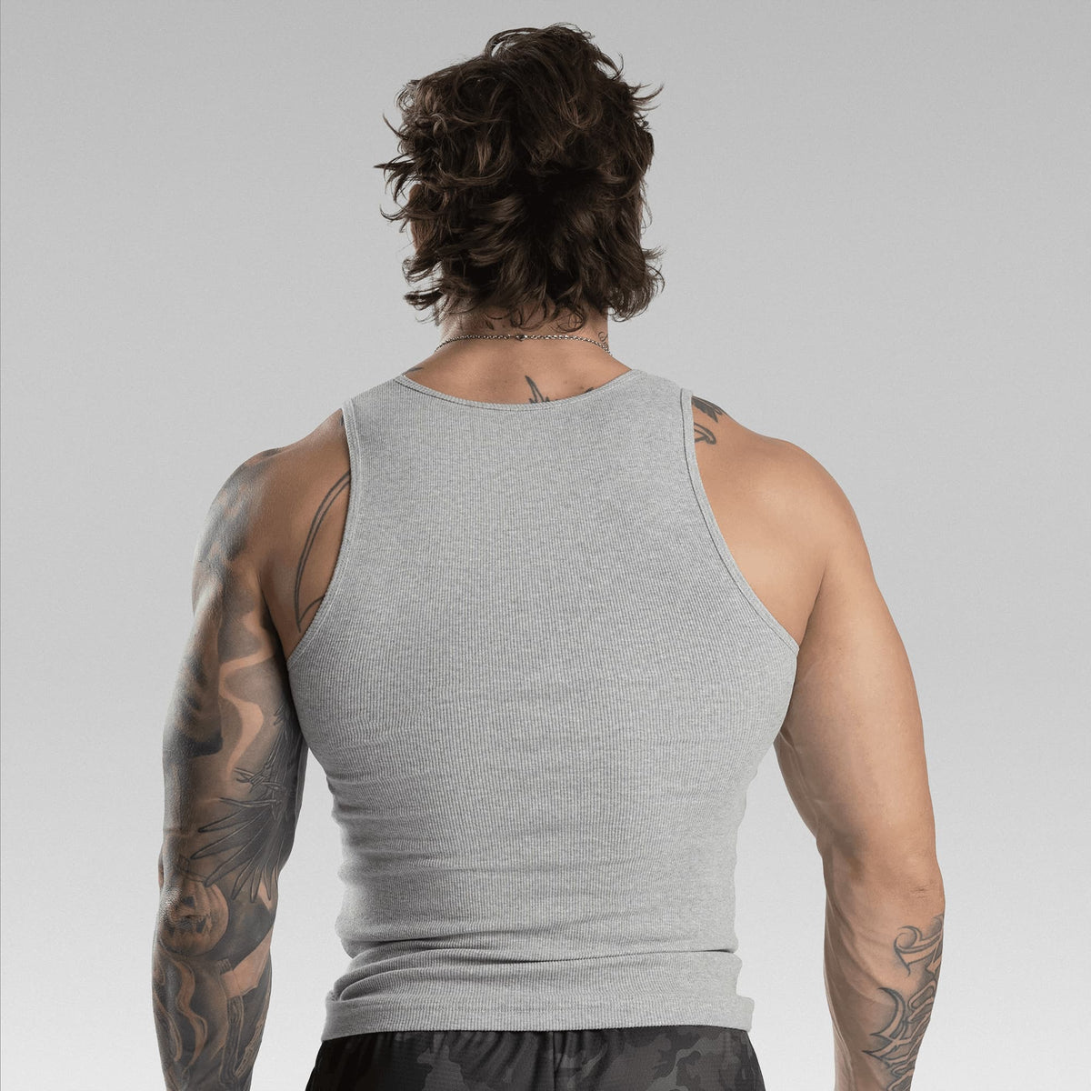 A man viewed from behind wearing a light gray ribbed tank top, showing the back of the garment.