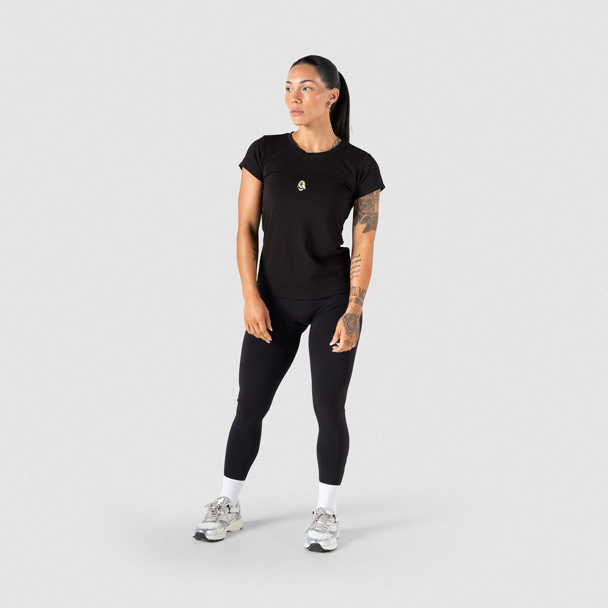 Full body view of Champions Gold Full Length Training Tee for women, paired with black leggings