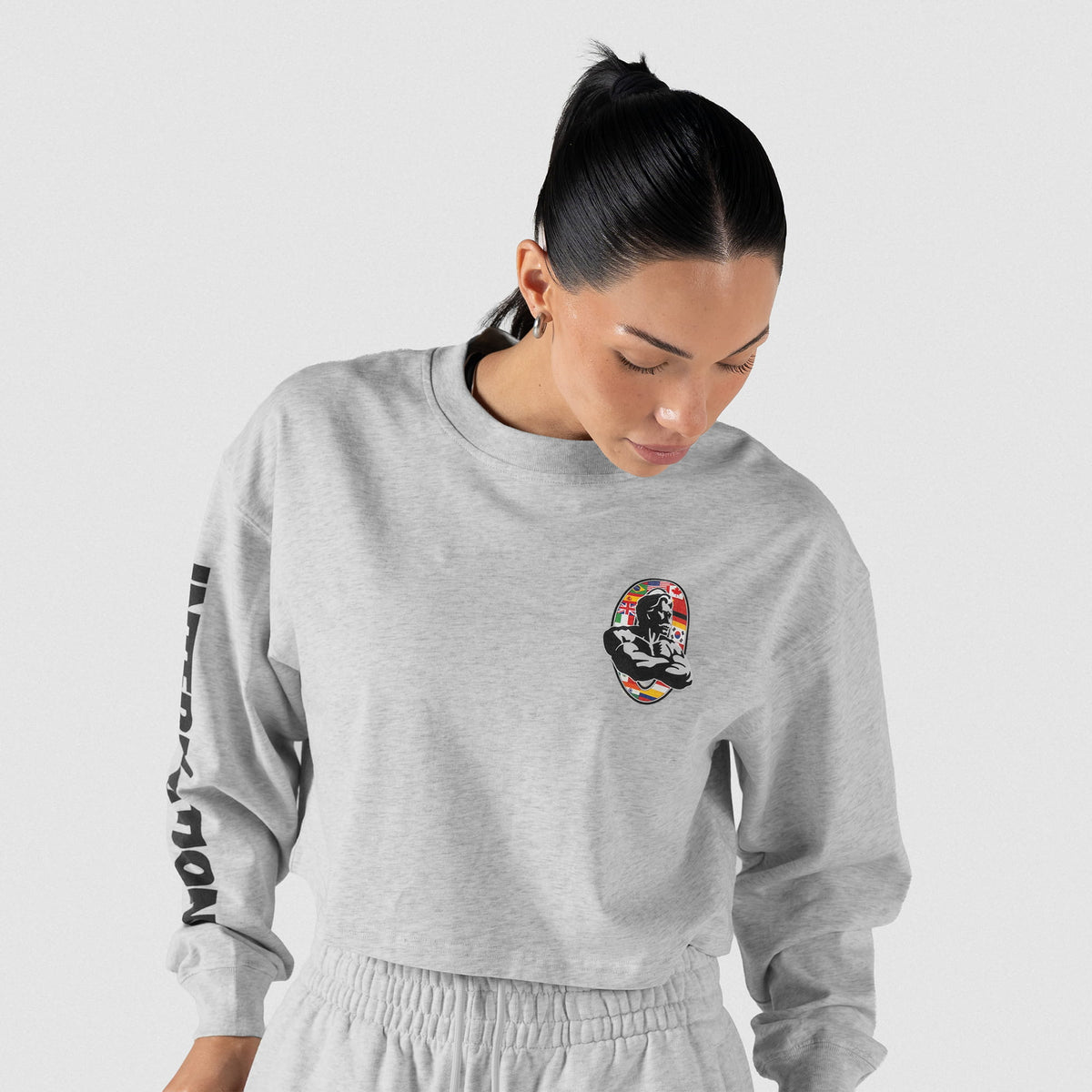 Female model wearing the Olympia International Division Crop Long Sleeve in gray