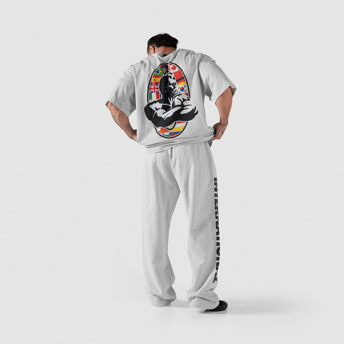 Olympia International Division Straight-Leg Jogger in gray on a male model, with a matching gray International Division Olympia t-shirt