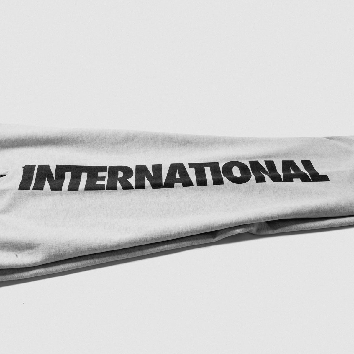 Close up view of the "International" wordmark logo that goes down the side of the right pant leg on the Olympia International Division Straight-Leg Jogger