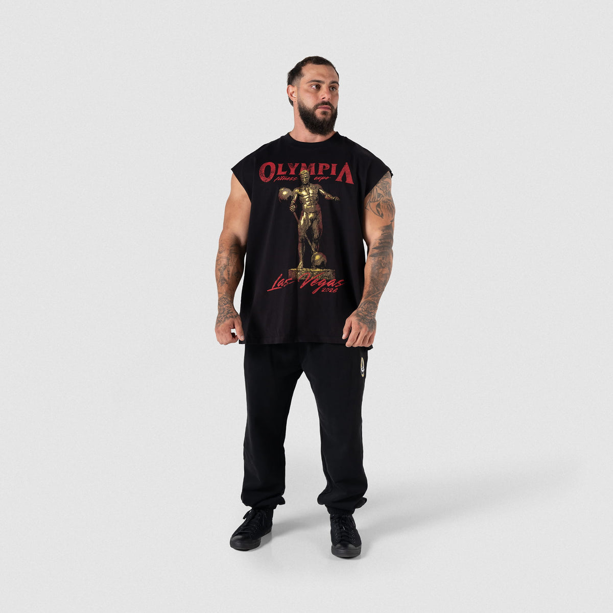 Male model wearing the black Olympia 2026 Sandow Cut-Off tank with black joggers