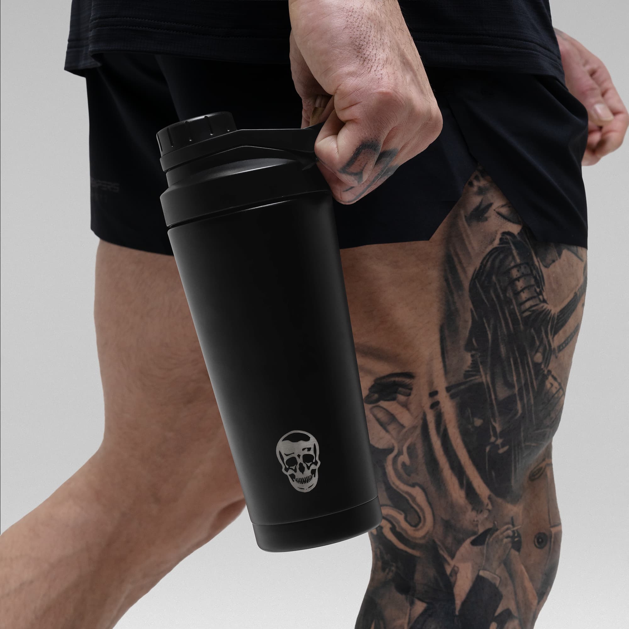 Athlete holding the Black Stainless Steel Shaker by the built in carry loop showcasing skull logo