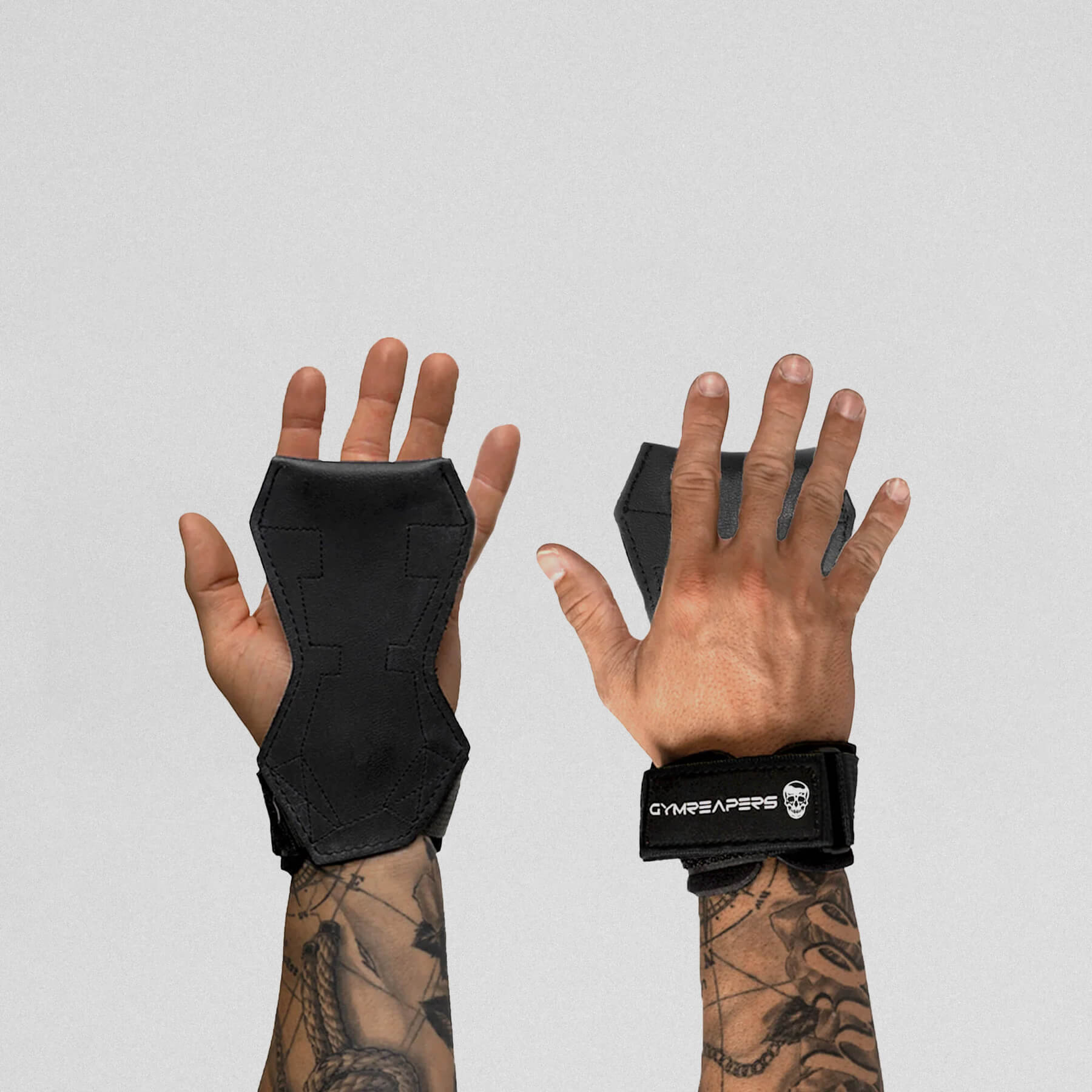 Gymreapers lifting grips black on hands, one hand facing down and the other facing up to showcase both ends of the grips.