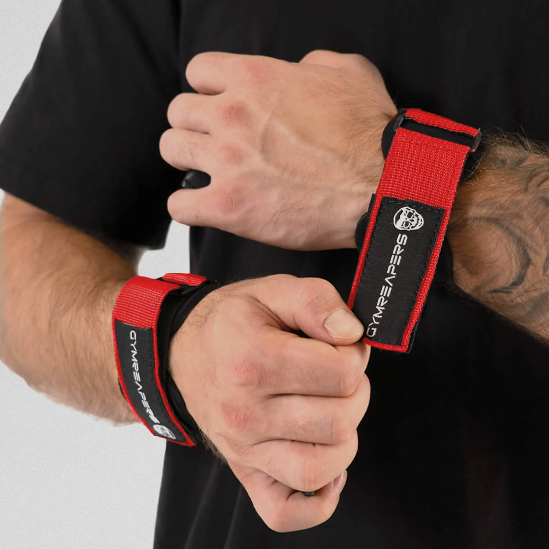 Gymreapers athlete attaching grips onto wrist, while the other one has it on already.